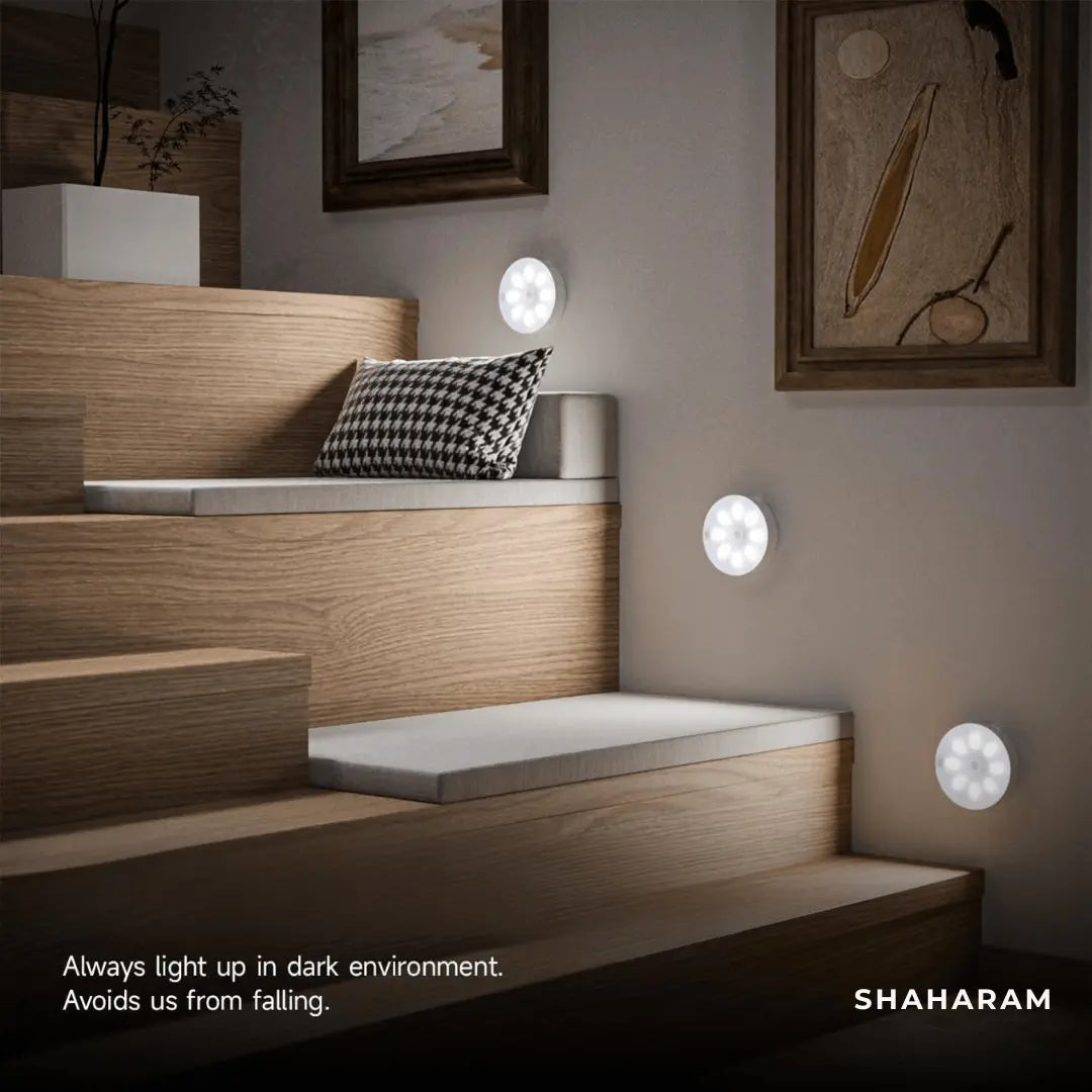 Multiple cool white motion sensor LED lights mounted along a wooden staircase wall for step safety.
